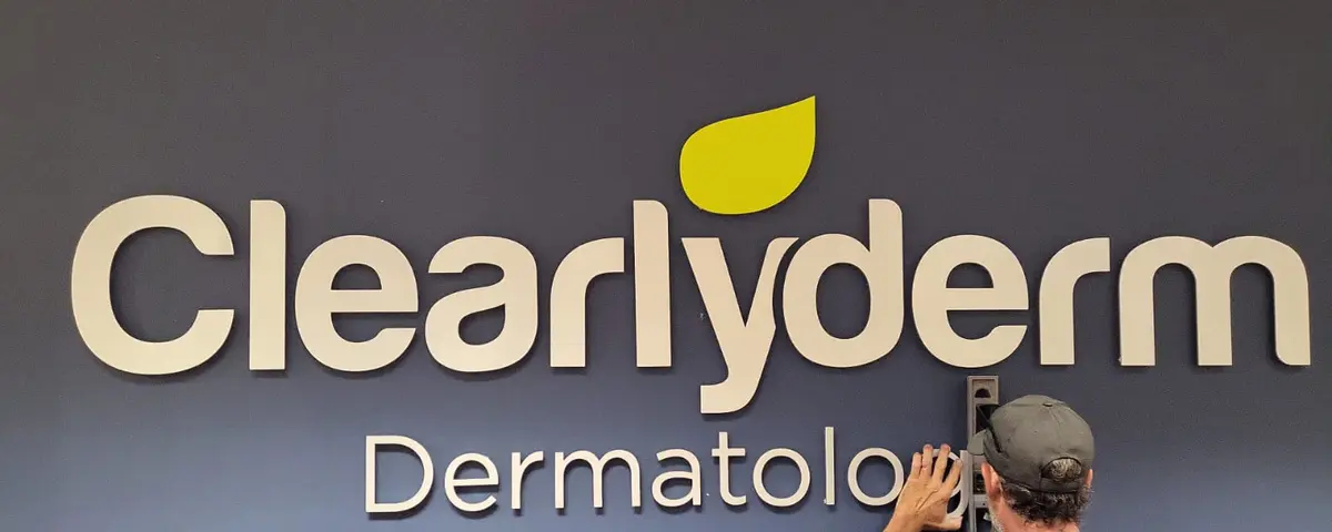 Installer mounting Clearlyderm Dermatology letters on a wall